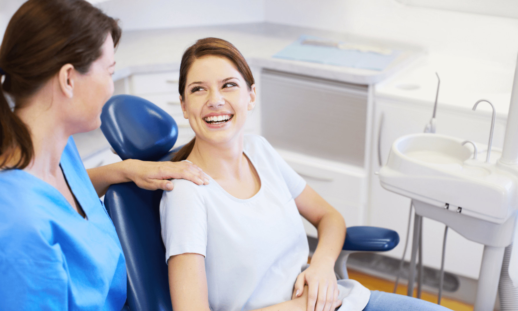 - A smiling woman with composite bonds sat in a dentist chair